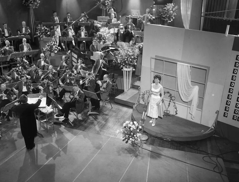 Lys Assia auf der Bühne des Eurovision Song Contest 1958 in Hilversum, davor das Orchester