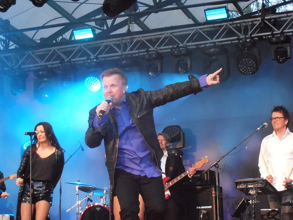 Richard Herrey singt mit ausgestrecktem Arm auf der Bühne im Eurovision Village Stockholm 2016