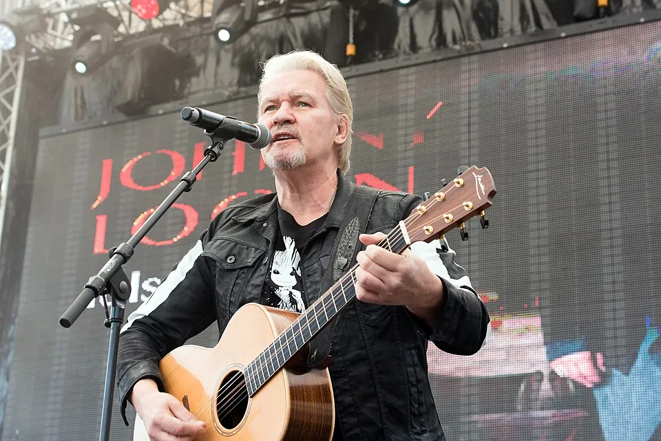 Johnny Logan singt mit Akustikgitarre am Mikrofon auf einer Open-Air-Bühne in Hamburg, 2017
