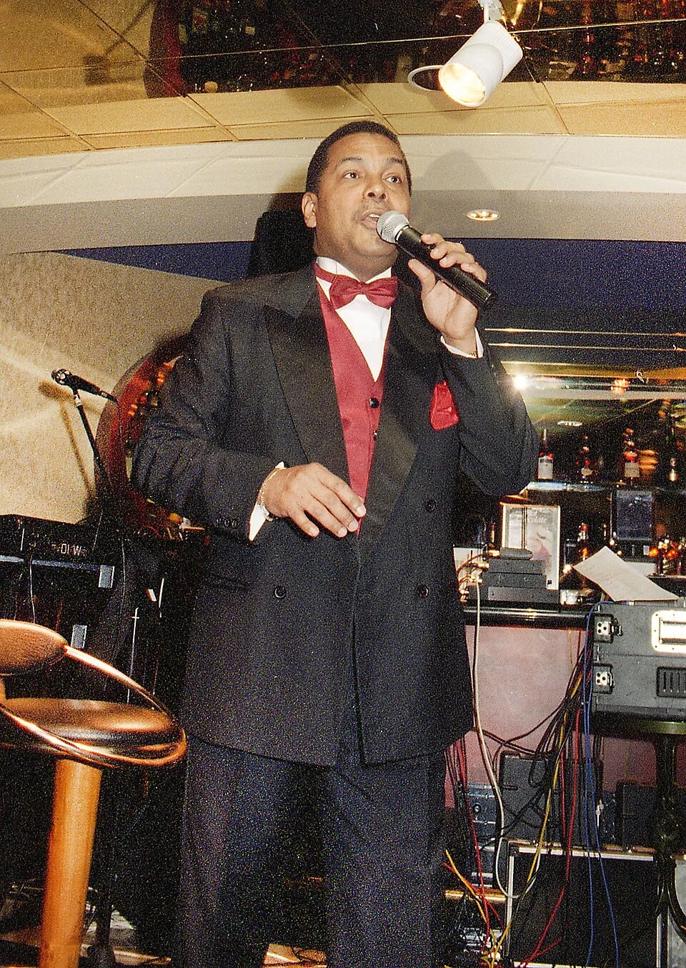 Dave Benton im dunklen Anzug mit roter Fliege singt mit Mikrofon, 1999