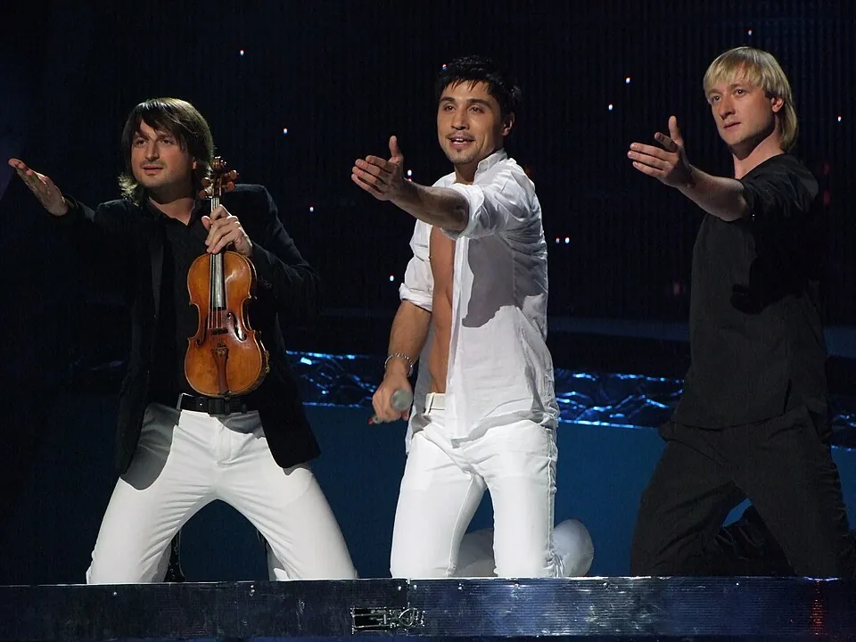 Dima Bilan im weißen Hemd zwischen Geiger und Eiskunstläufer auf der ESC-Bühne 2008 in Belgrad