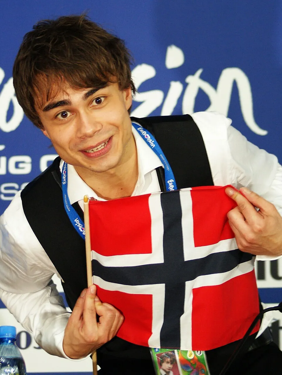 Alexander Rybak hält lächelnd eine norwegische Flagge bei der ESC-Pressekonferenz 2009 in Moskau