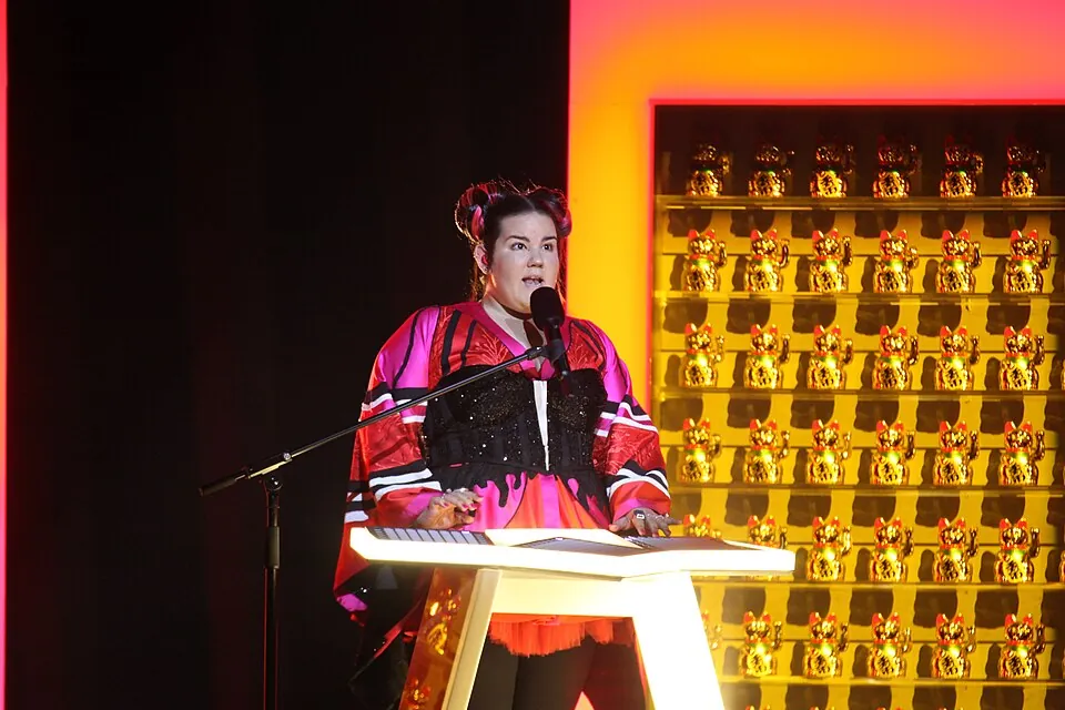 Netta im pink-schwarzen Kimono-Outfit am Looper-Pult vor einer Wand mit Winkekatzen, ESC 2018