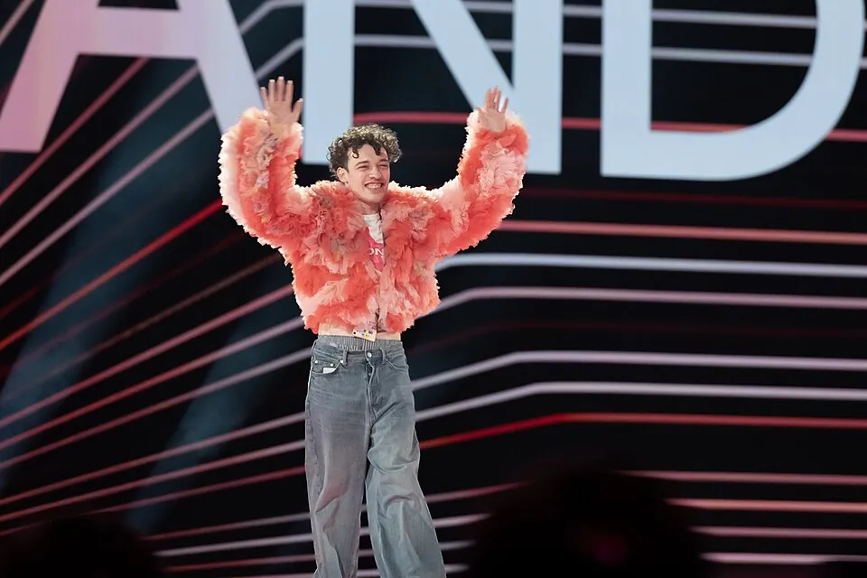 Nemo in pinker Federjacke und weiter Jeans reckt beide Arme hoch, Generalprobe ESC 2024 in Malmö